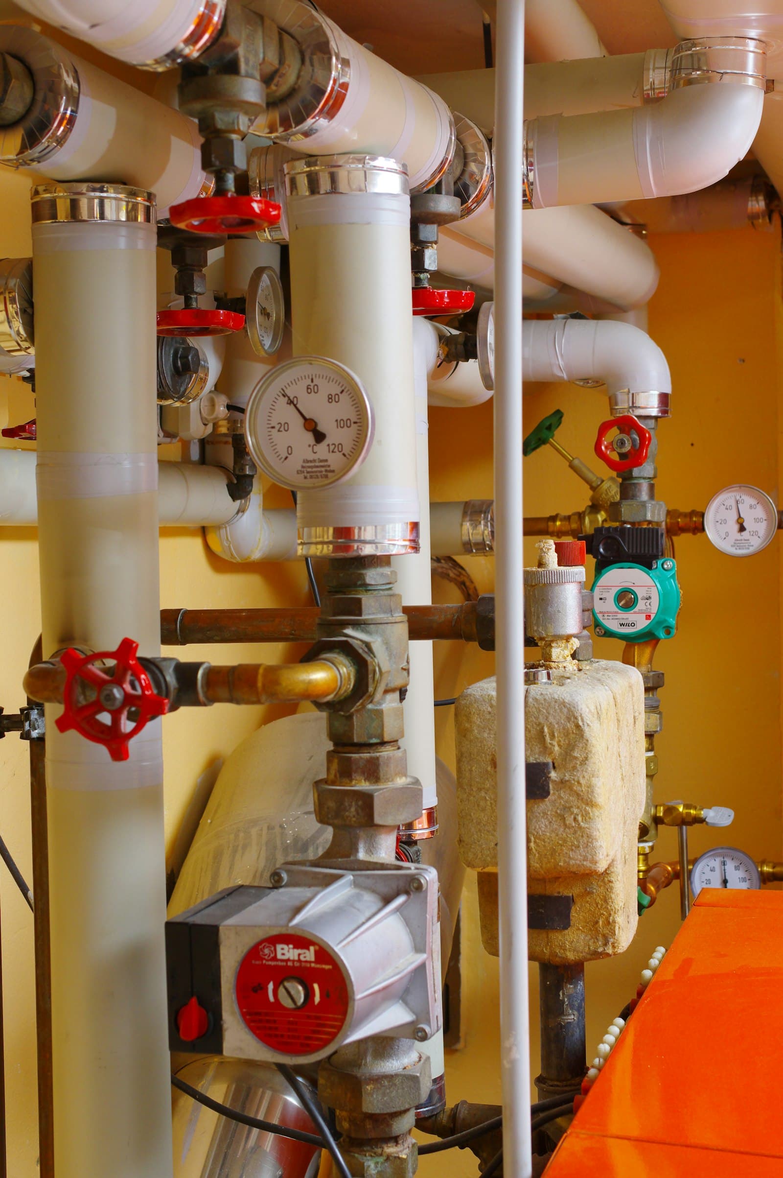 Interior mechanical room with exposed gas piping and pressure gauges in a residential building