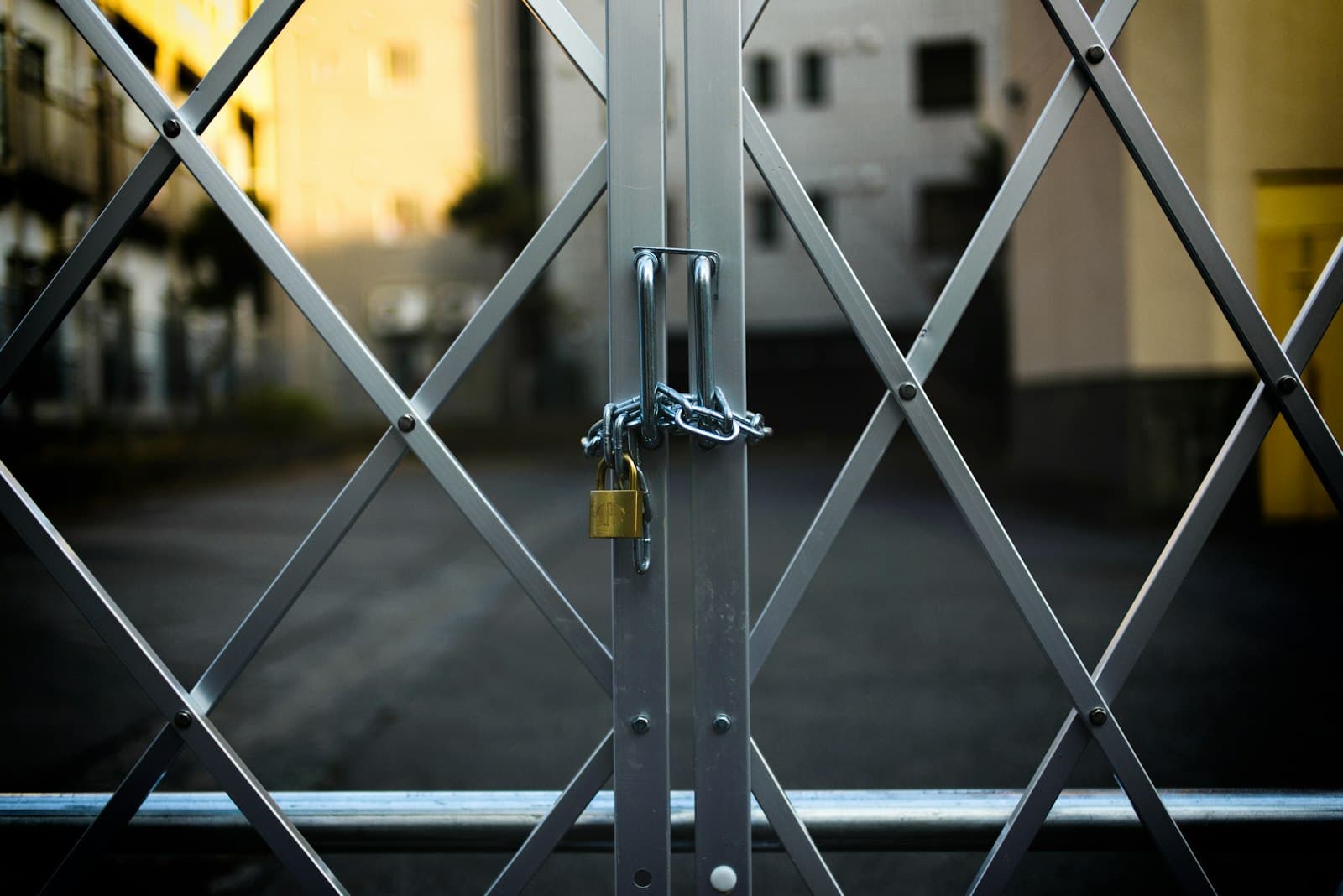 Closed steel security gate on a storefront secured with a padlock